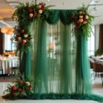 Sheer white wedding arch draping fabric elegantly draped over a wooden arch at an outdoor ceremony