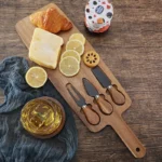 Acacia cheese board set with cheese knives and wooden cutting board on a table