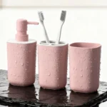 Coordinating pink toothbrush holder with gold accents, holding two toothbrushes.
