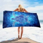 Blue star turtle quick dry beach towel on sand with ocean background