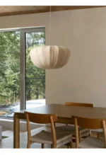 Wabi sabi pendant light hanging over a wooden dining table in a cozy room