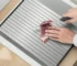 Folding dish drying rack with stainless steel roll-up design and cutting board on kitchen counter
