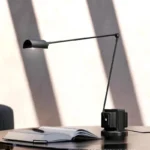 Italian design replica floor lamp in black, placed in a modern living room with sofa and coffee table.