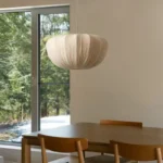 Wabi sabi pendant light hanging over a wooden dining table in a cozy room