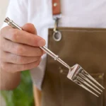 Set of 12 stainless steel forks arranged neatly on a wooden table