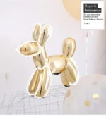 Balloon dog sculpture on a shelf next to a framed photo and small plant.