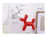 Balloon dog statue on a rustic wooden shelf with other decor items.