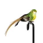 Black and white fake bird with red accents, displayed on a garden statue pedestal in a backyard.