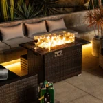 Rectangular propane fire pit table with tile top and wicker base on patio