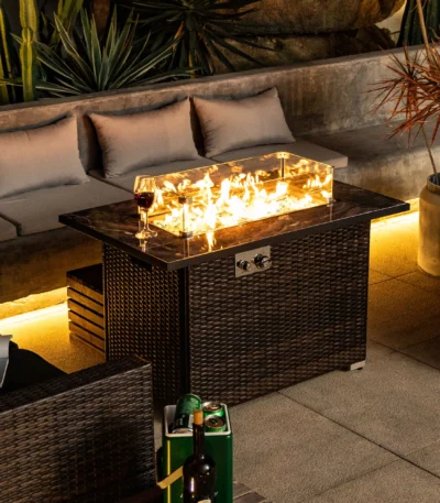 Rectangular propane fire pit table with tile top and wicker base on patio