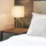Modern gold table lamp with linen shade on bedside table in bedroom