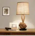 Vintage table lamp with hemp rope and iron base, emitting warm light on a bedside table