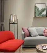 Modern floor lamp with iron frame and glass shade in a cozy living room