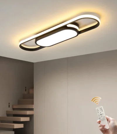 Modern LED linear ceiling light in white acrylic, mounted on a gray ceiling, glowing warmly in a living room setting.