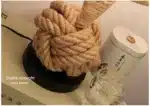 Vintage table lamp with hemp rope and iron base, emitting warm light on a bedside table