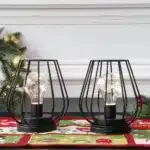 Set of two metal cage table lamps with warm glow on wooden table