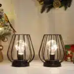Set of two metal cage table lamps with warm glow on wooden table