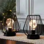 Set of two metal cage table lamps with warm glow on wooden table