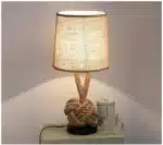 Vintage table lamp with hemp rope and iron base, emitting warm light on a bedside table