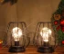 Set of two metal cage table lamps with warm glow on wooden table