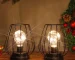 Set of two metal cage table lamps with warm glow on wooden table
