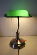 Antique bronze table lamp with green shade on bedside table