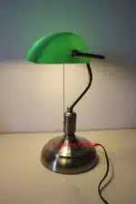Antique bronze table lamp with green shade on bedside table