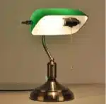 Antique bronze table lamp with green shade on bedside table