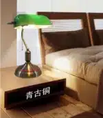 Antique bronze table lamp with green shade on bedside table