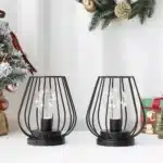 Set of two metal cage table lamps with warm glow on wooden table