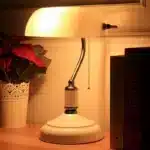 Antique bronze table lamp with green shade on bedside table