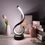 Modern desk lamp with adjustable arm and USB cable, glowing warmly on a wooden desk