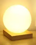Modern table lamp with iron body and wood base illuminating a cozy bedroom