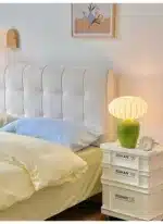 Vintage table lamp with retro ceramic base and silk shade on bedside table in cozy bedroom
