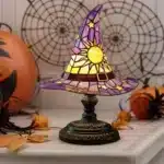 Witch hat lamp with stained glass pattern casting a warm glow on a bedside table
