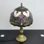 Tiffany table lamp with tulip stained glass shade, rustic bronze base, glowing warmly