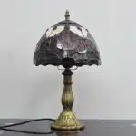 Tiffany table lamp with tulip stained glass shade, rustic bronze base, glowing warmly