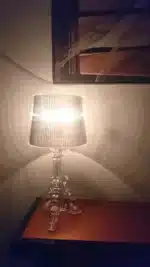 Modern acrylic table lamp glowing softly on a bedside table in a contemporary bedroom