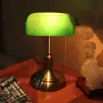 Antique bronze table lamp with green shade on bedside table