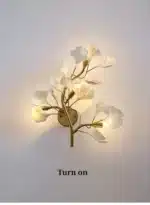 Luxury gold leaf sconce with modern ginkgo design illuminating a living room wall