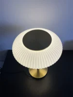 White glass table lamp with vintage design on a wooden desk in a cozy bedroom