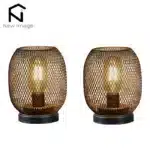 Battery table lamp with metal cage and warm LED glow on a wooden table