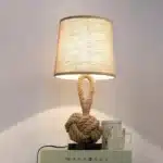 Vintage table lamp with hemp rope and iron base, emitting warm light on a bedside table