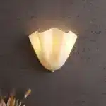Modern wall sconce with shell-shaped glass and LED light in a minimalist living room