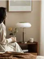 White glass table lamp with vintage design on a wooden desk in a cozy bedroom