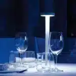 Modern rechargeable table lamp glowing warmly on a wooden bedside table