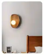 Vintage wall sconce with wooden backplate and clear glass shade, warm light