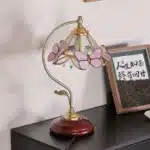 Vintage desk lamp with stained glass butterfly shade casting warm glow on bedside table