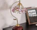 Vintage desk lamp with stained glass butterfly shade casting warm glow on bedside table