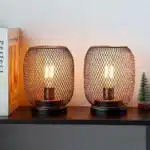 Battery table lamp with metal cage and warm LED glow on a wooden table